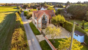 Une maison avec un toit recouvert de tuiles rouges, des fondations en pierre et un petit jardin avec un chemin menant à l’entrée.