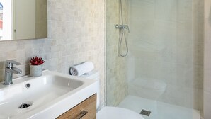A modern bathroom with a glass-enclosed shower, a white sink with a wooden cabinet, and a toilet. - Genteel Home Baños Terrace (Seville)