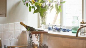 Een keuken met een wijnfles in een emmer, een vaas met bloemen en een raam met uitzicht.
