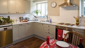 Een keuken met witte kastjes, een roestvrijstalen afzuigkap en een raam voor natuurlijk licht.