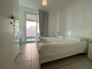 Une chambre à coucher avec un lit, une table de chevet, une porte et une vue sur l’extérieur.