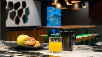 A breakfast setting with a plate of food, a glass of orange juice, and a mug on a marble countertop.