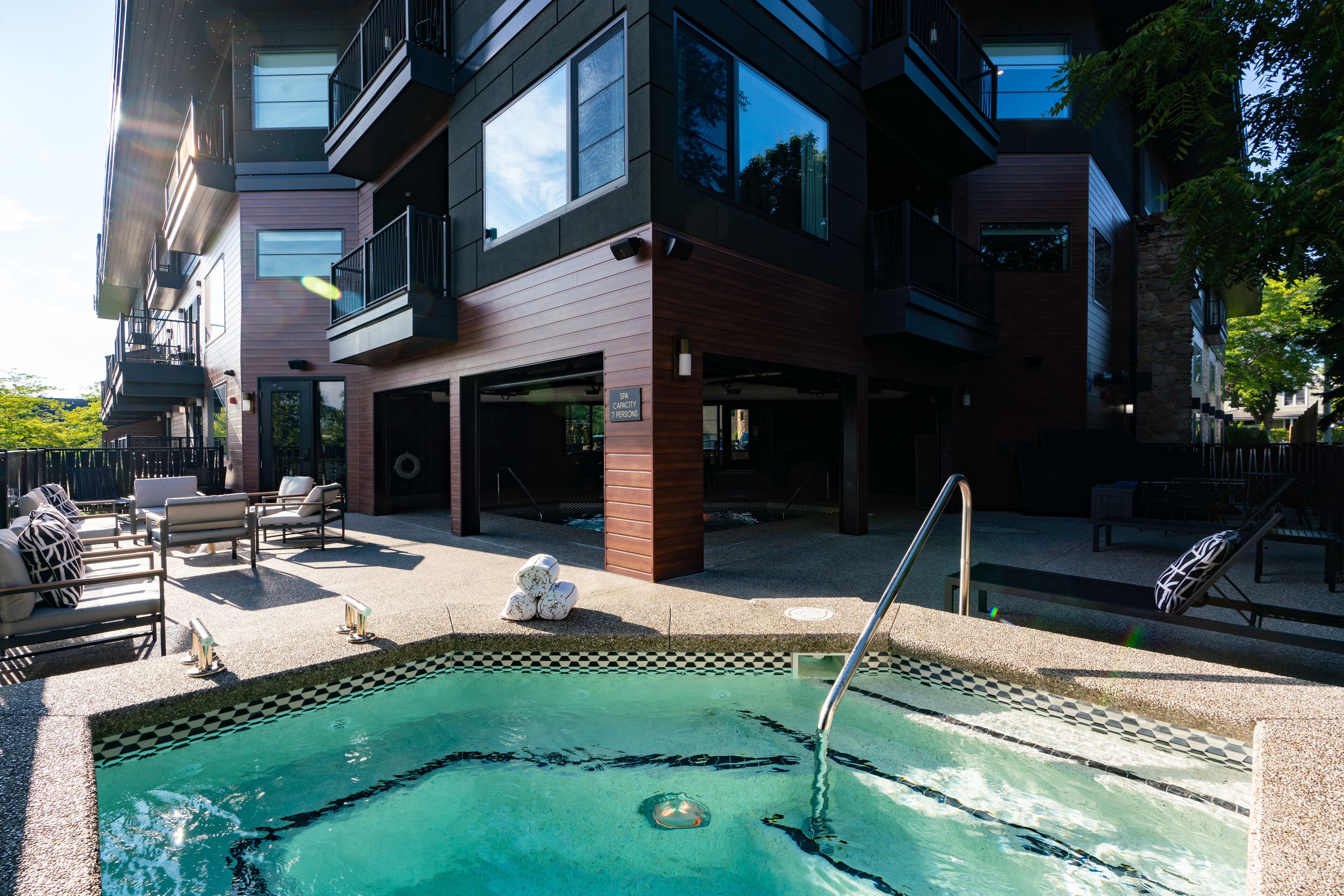 Um edifício moderno com piscina, área de estar externa e fachada de pedra.