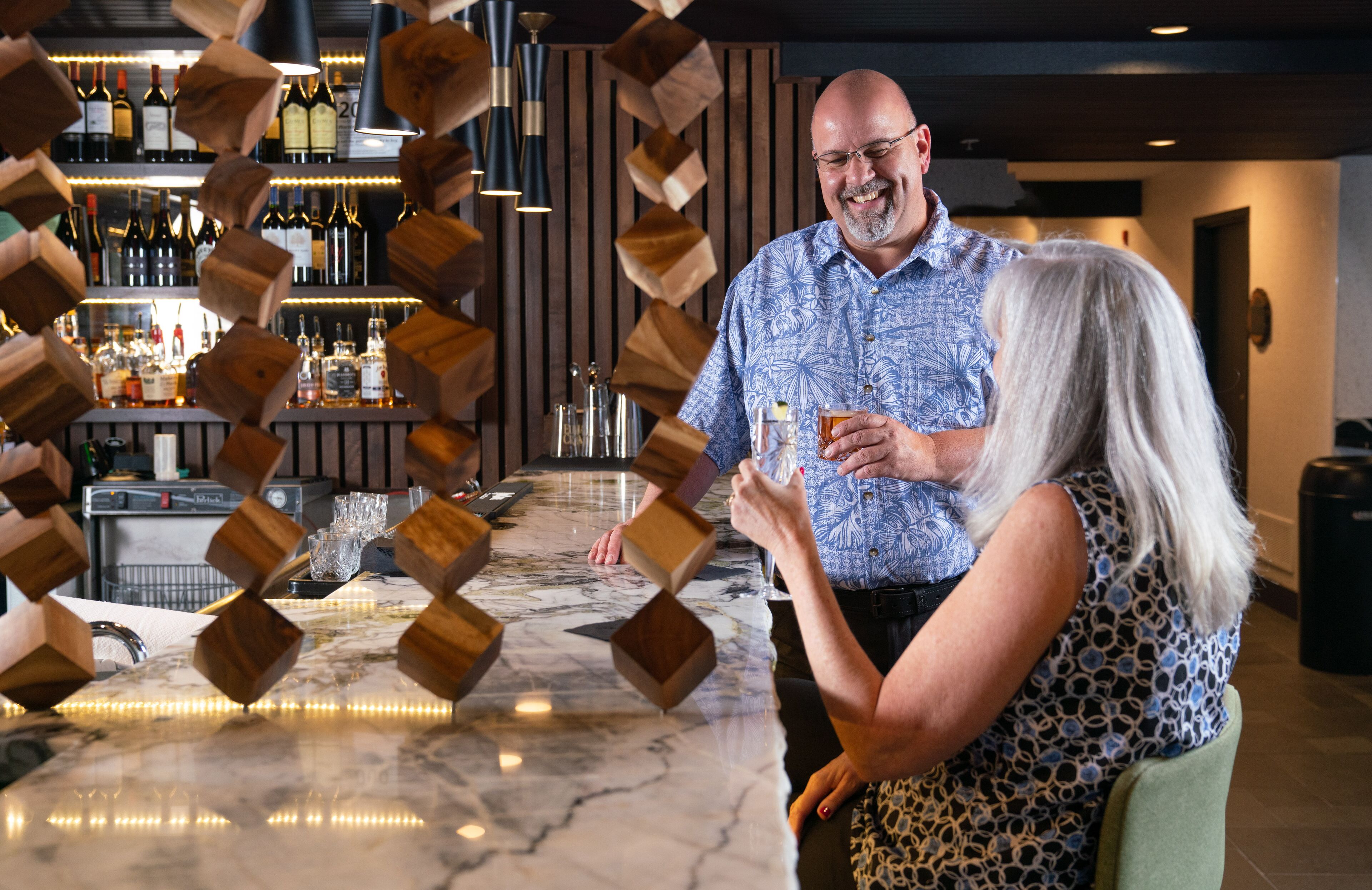 Un espace bar agrémenté de blocs de bois, d’un comptoir en marbre et d’un meuble à vin en arrière-plan.