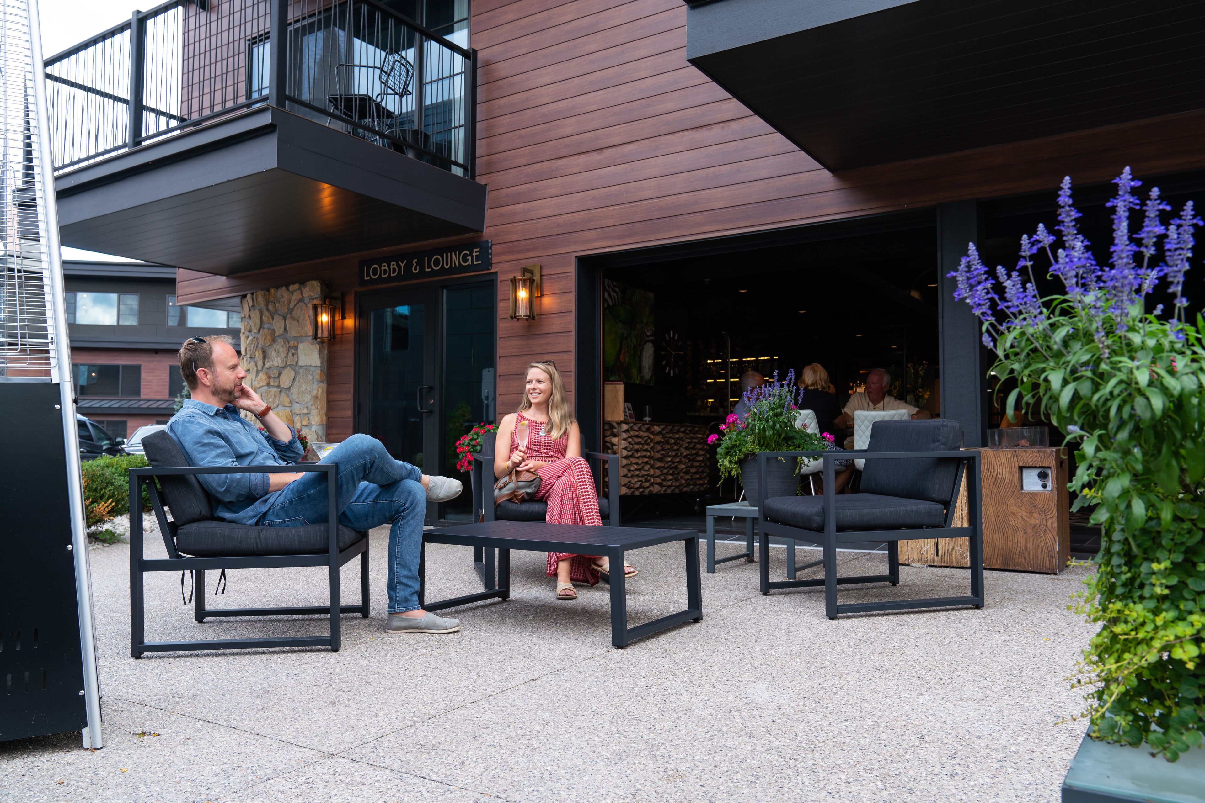 An outdoor seating area with modern furniture, a stone wall, and a sign for 'Lobby & Lounge'.