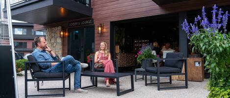 An outdoor seating area with modern furniture, a stone wall, and a sign for 'Lobby & Lounge'.