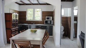 A modern kitchen with a dining table, wooden cabinets, and a microwave.