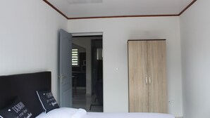 A bedroom with a bed, a wardrobe, and an open door leading to a hallway.