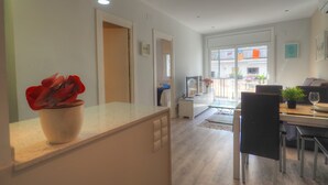 A modern kitchen with a countertop, a potted plant, and a dining area with a table and chairs.