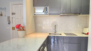 A modern kitchen with a built-in microwave, stainless steel cabinets, a sink, and a potted plant.