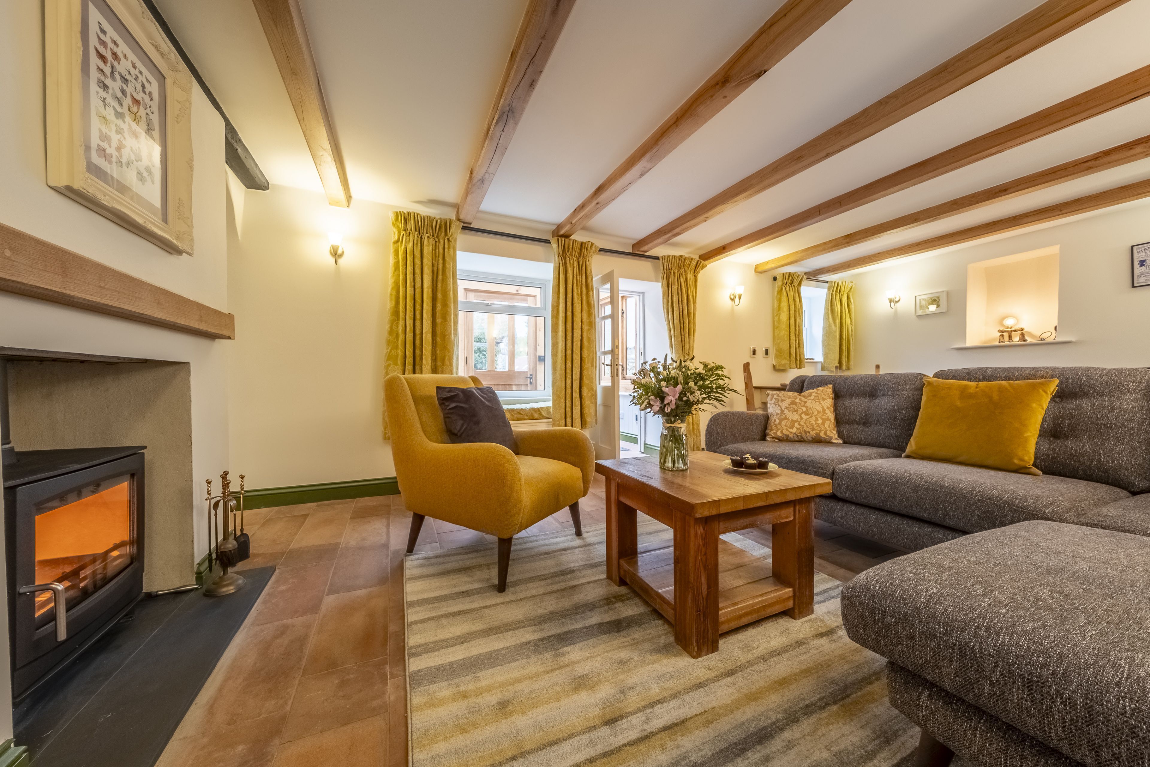 A cozy living room with a fireplace, a sofa, a yellow armchair, and a wooden coffee table.