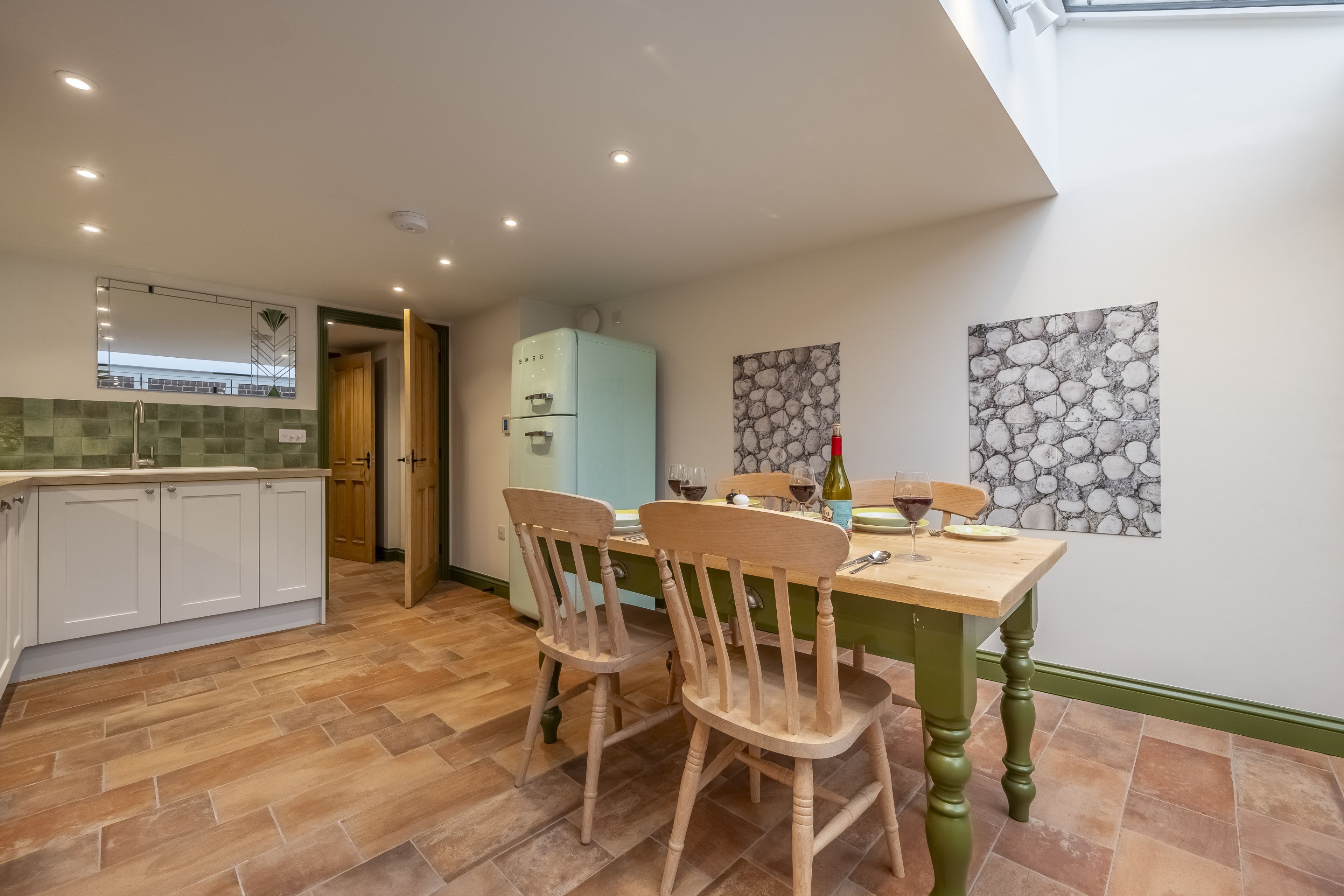Une cuisine moderne avec un coin repas, comprenant une table en bois, des chaises et un réfrigérateur.