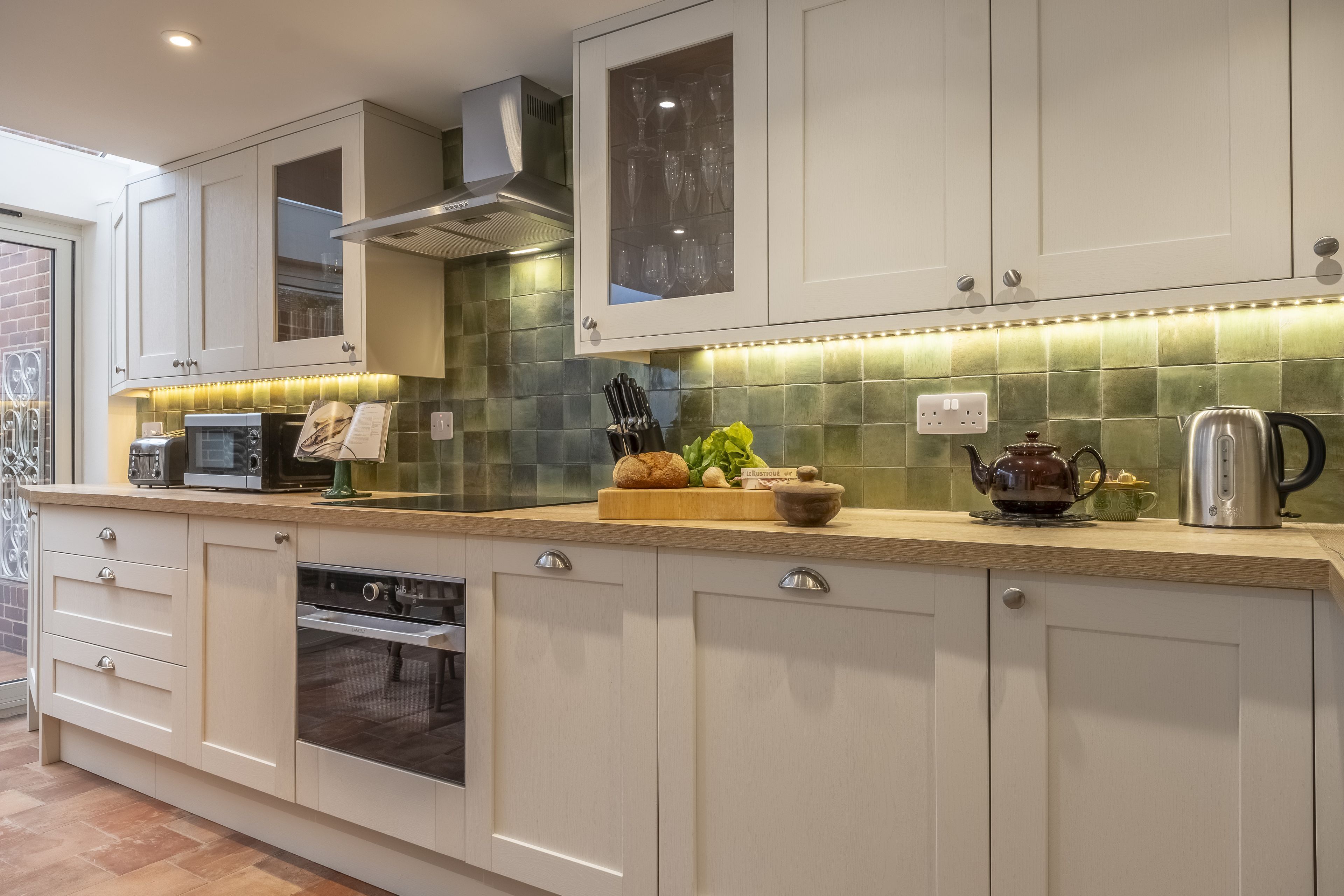 A modern kitchen with white cabinets, a built-in oven, a microwave, and a countertop with various kitchen items.