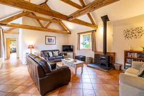 Una sala de estar con chimenea, sofás de cuero, televisor y estantería.