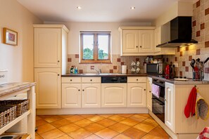 A kitchen with white cabinets, a window, a dishwasher, a microwave, and a stove.