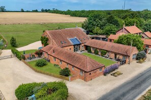 A large brick house with a spacious yard, a driveway, and a solar panel on the roof.