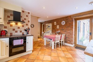 Una cucina con zona pranzo, caratterizzata da un rivestimento in piastrelle, un forno integrato e un tavolo da pranzo con sedie.