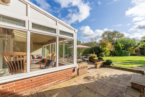 A modern house with large windows, a patio with outdoor furniture, and a well-maintained garden. - Columbine Cottage, Holme-next-the-Sea, Norfolk (Hunstanton)