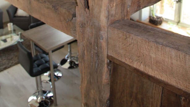 A rustic wooden beam structure in a room with a modern bar area and a view of the outdoors. - Apartment on the Elbe dyke in Radegast I (Bleckede)