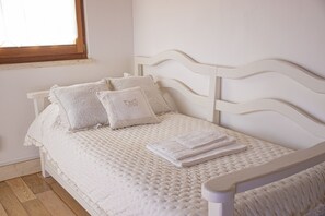 Un lit bien fait, avec une couverture matelassée, des oreillers et des serviettes pliées.