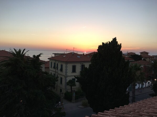 Une ville côtière au coucher du soleil, avec des bâtiments et un ciel dégagé.