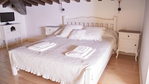 Un dormitorio con una cama grande, dos mesitas de noche, un televisor y una lámpara.