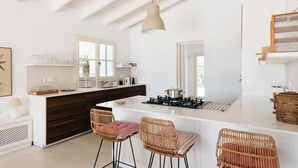 Una cucina moderna con isola centrale, sgabelli da bar e lampada a sospensione.