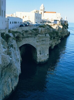 A coastal town with a prominent white church and a stone bridge over the water.