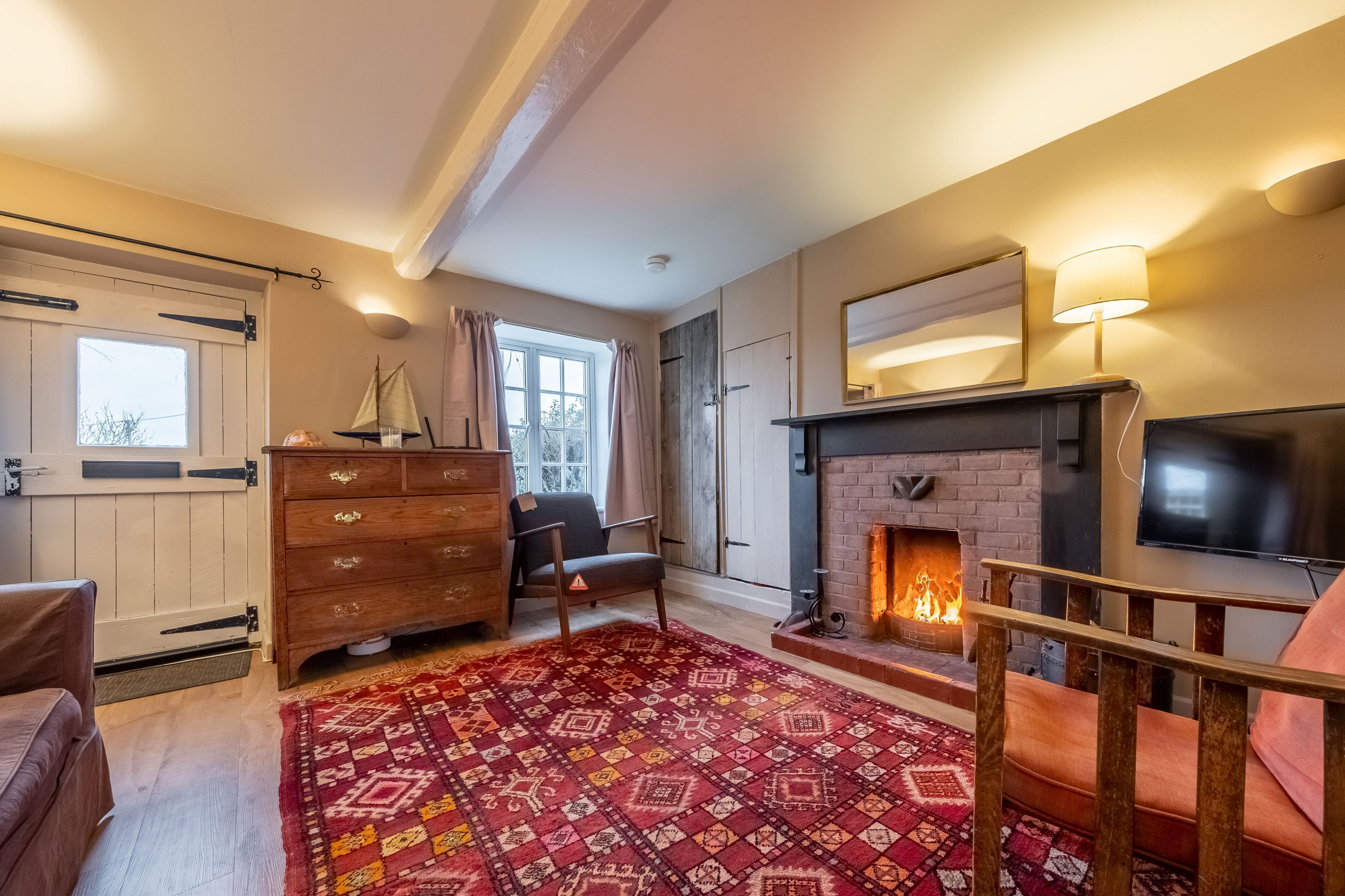 Un salon chaleureux avec une cheminée, des meubles en bois et un tapis à motifs.