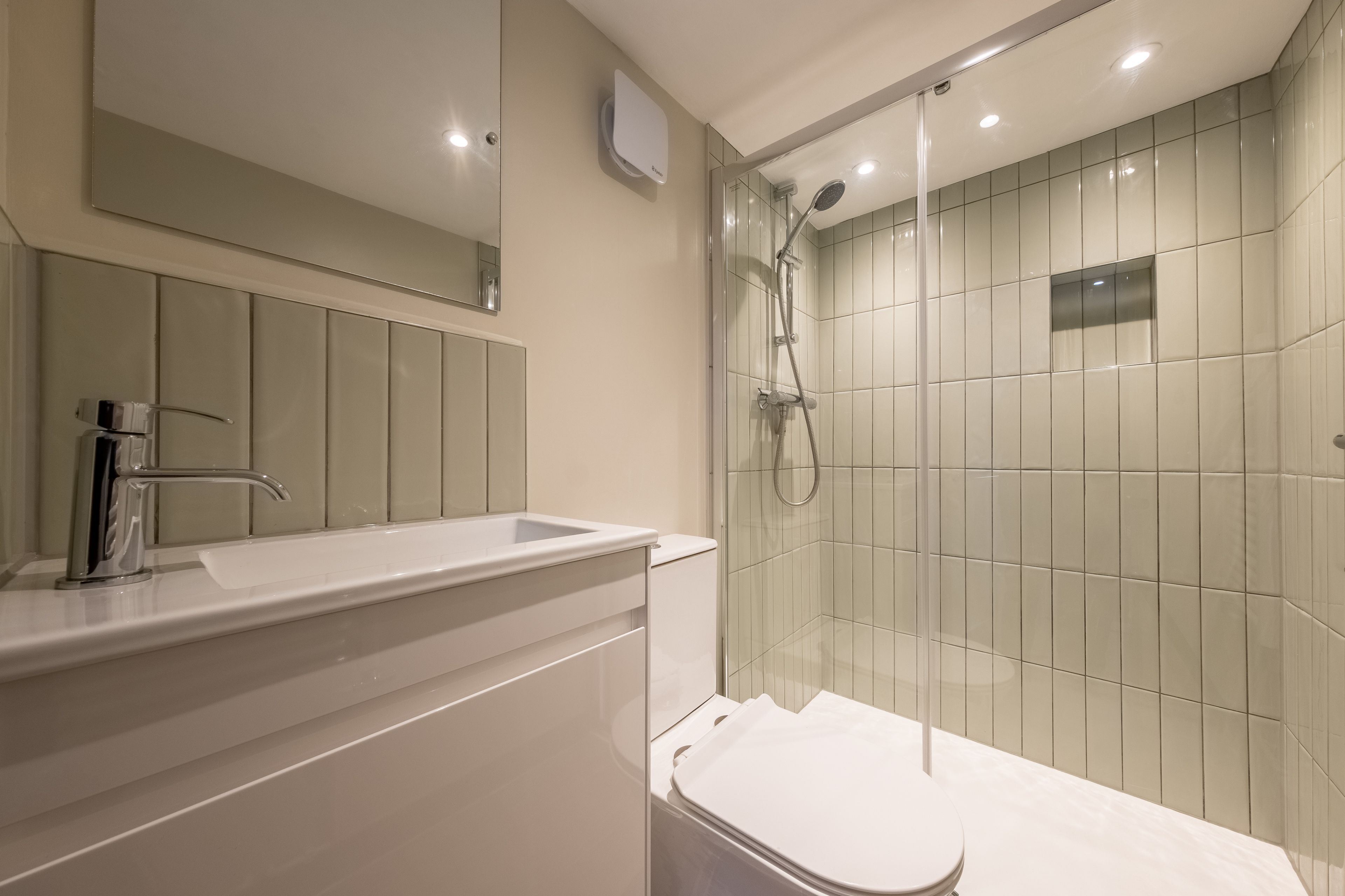A modern bathroom with a glass-enclosed shower, a white sink, and a toilet.