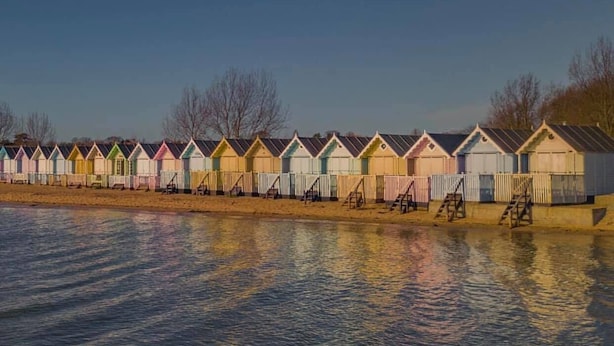 Una hilera de cabañas de playa coloridas a lo largo de la costa.