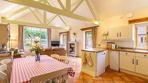 A cozy kitchen with a dining area, a TV, and a view of the garden. - The Cart Lodge, Great Massingham, Norfolk (King's Lynn)