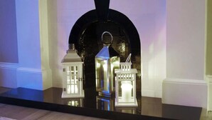A fireplace with a black arch and two lit lanterns on a reflective surface. - Ayr Beach View Apartment (Ayr)