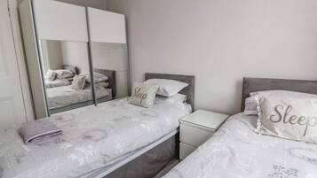 Un dormitorio con dos camas individuales, una mesita de noche, un espejo y un armario.