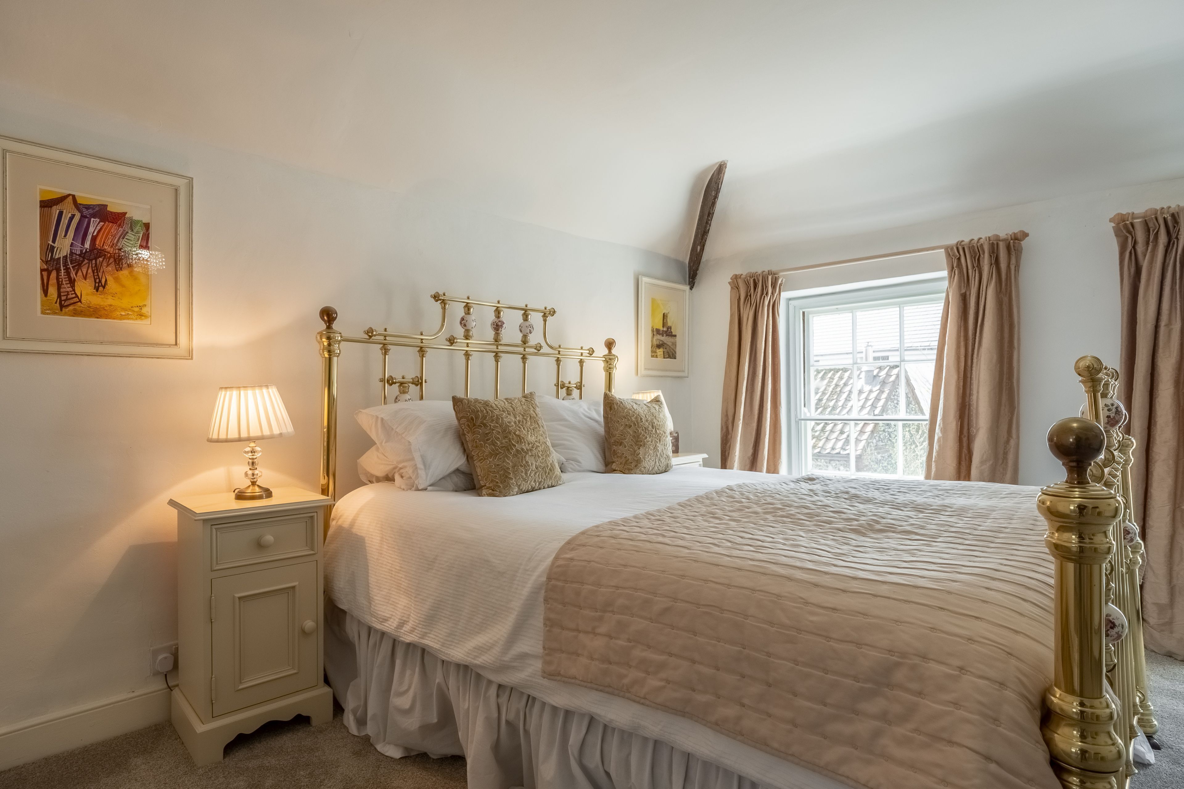 A bedroom with a bed, nightstand, and a window with curtains.