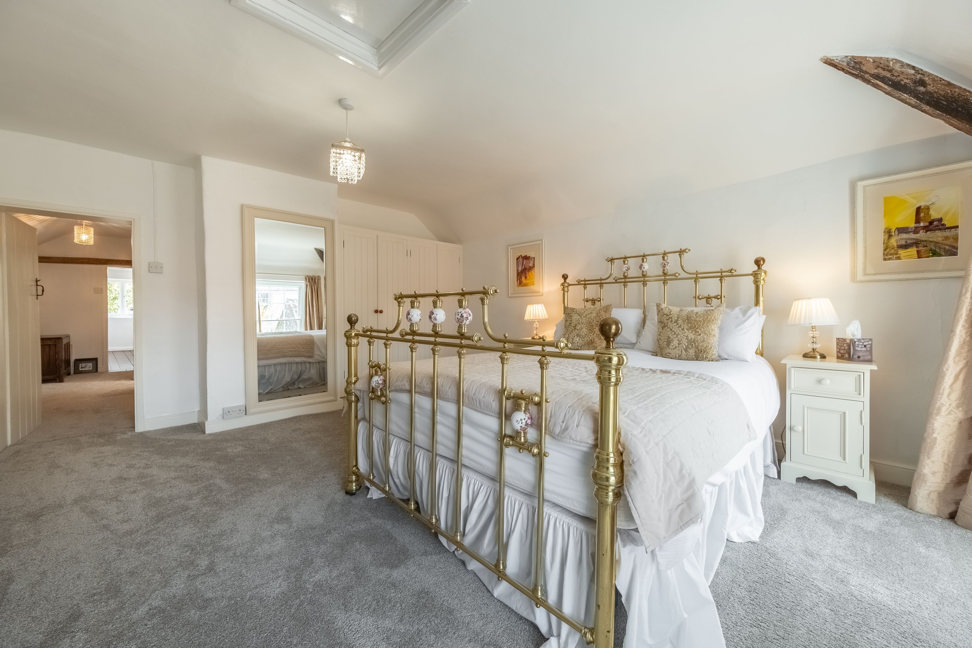 A bedroom with a four-poster bed, a nightstand, a lamp, and a painting on the wall.