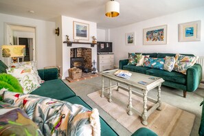 A cozy living room with a fireplace, green sofa, and a coffee table. - Duck Cottage, South Creake, Norfolk (South Creake)