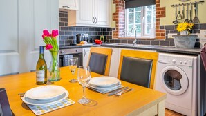 A kitchen with white cabinets, a brick backsplash, a window, and a washing machine.