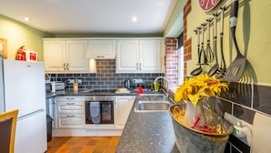 A kitchen with white cabinets, a black countertop, and a backsplash. There is a sink, a stove, and a refrigerator.