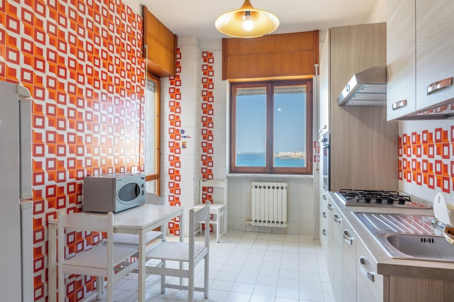 Una cocina compacta con vistas al mar, estufa integrada y comedor con mesa y sillas.
