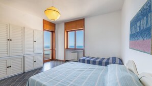 A bedroom with two beds, a window, a radiator, and a ceiling light. - Cozy apartment Blue Sunset sea view in Gallipoli CVG42 (Gallipoli)