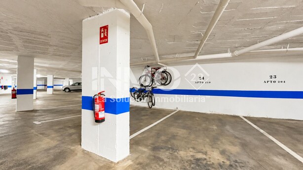 Un parking avec des piliers blancs, des bandes bleues et des places de stationnement numérotées.