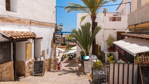 A narrow street with a restaurant named 'Tasca Moraira' and a sign for 'Meson El Pou'.