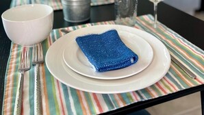 Mesa posta com uma tigela branca, um guardanapo azul e um prato branco.