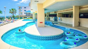 Una piscina con varias pistas de natación, sillones de descanso y flotadores inflables.