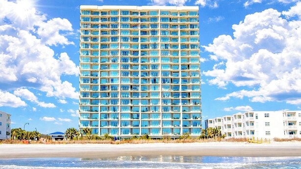 Un hotel moderno de gran altura, con múltiples balcones y un amplio frente de cristal.