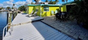 Un molo con sedie a sdraio, un piccolo edificio con una finestra e una zona pavimentata.