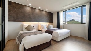 A modern hotel room with two beds, a large window with a mountain view, and a dark textured wall. - Andong CM Park Hotel (Yecheon)