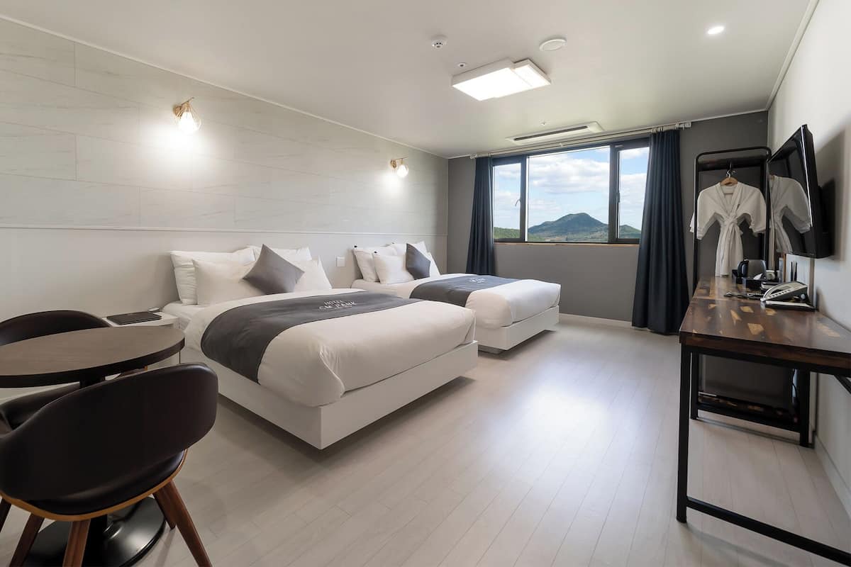 Habitación de hotel moderna con una cama grande, un escritorio y una silla. Se ve una ventana con vistas a las montañas.