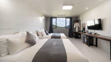 Quarto de hotel com duas camas, uma secretária e televisão, e vista para o exterior.